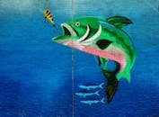 Vibrant mural of a fish and bait on a brick wall, showcasing street art in Dubai.