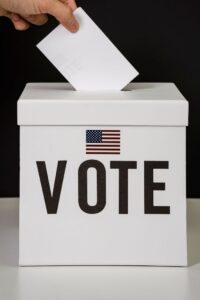 A person placing a ballot into a voting box, symbolizing democratic participation and civic duty.
